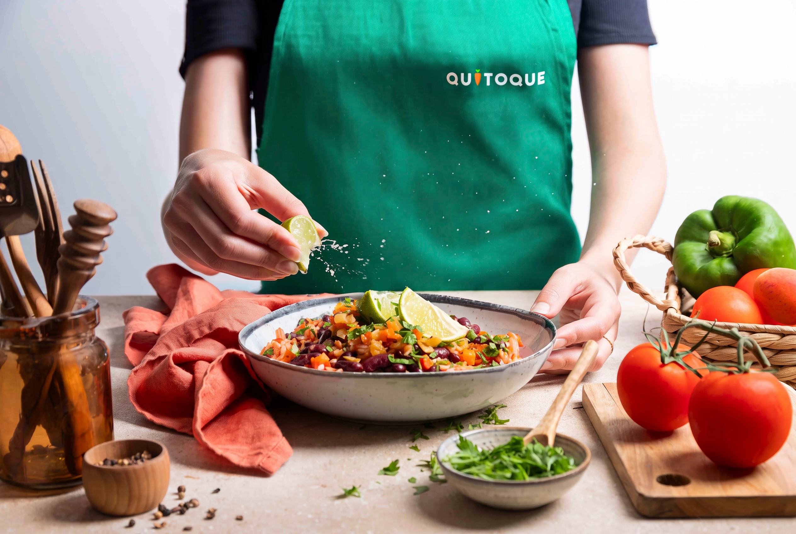Cuisinier en tablier Quitoque dressant une assiette dans son atelier